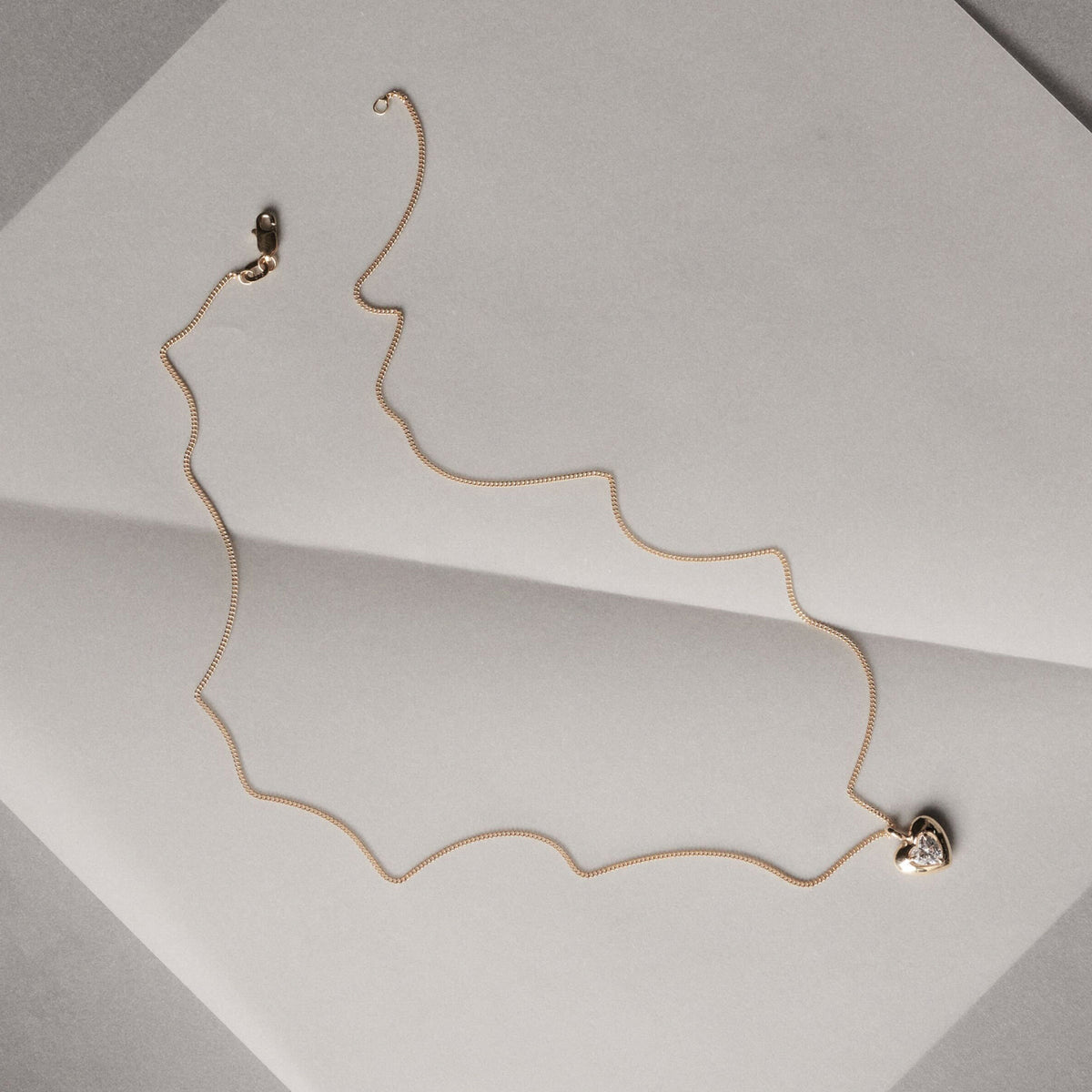Gold necklace on a light gray surface