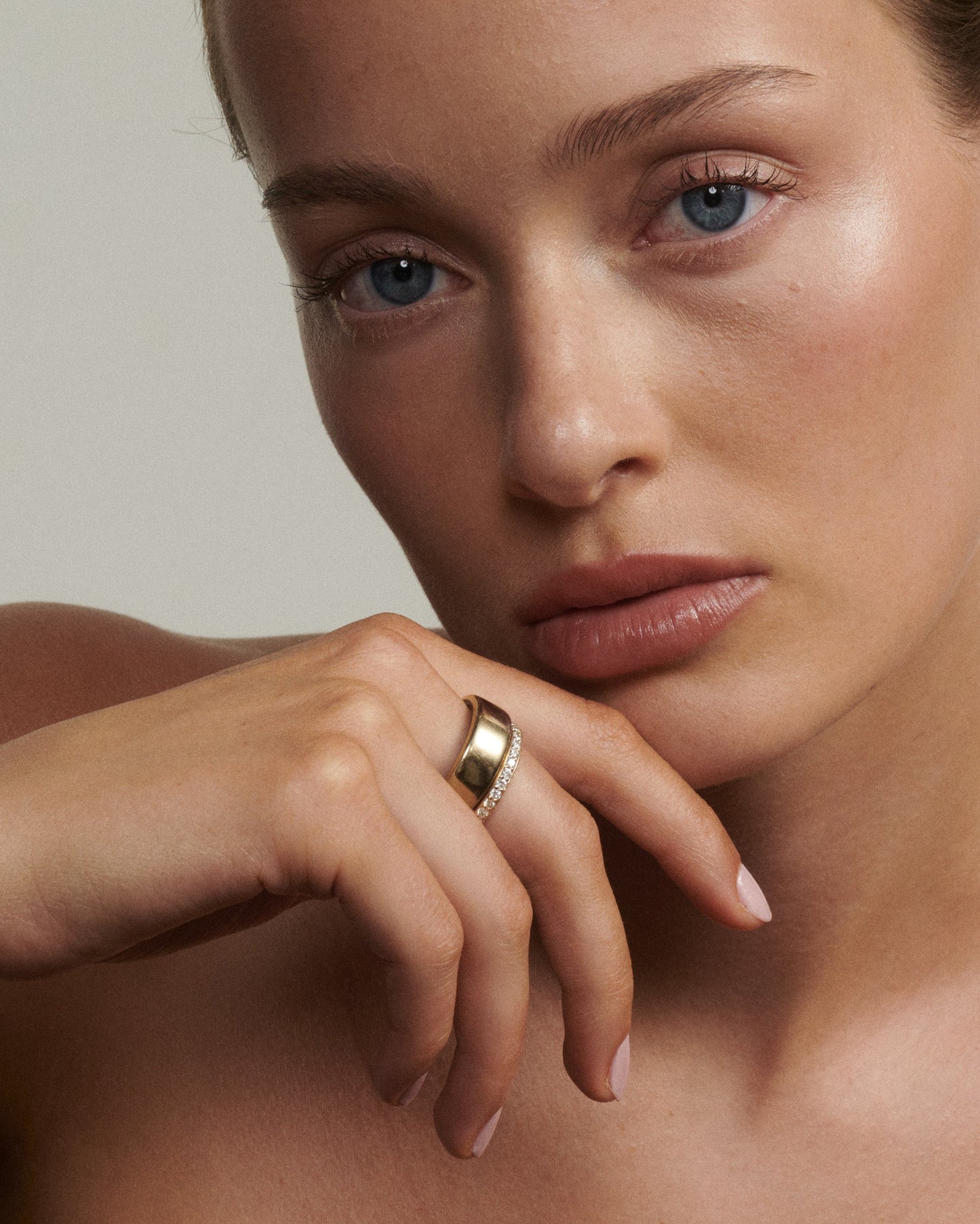 Close-up of a woman's face with a gold ring on her finger