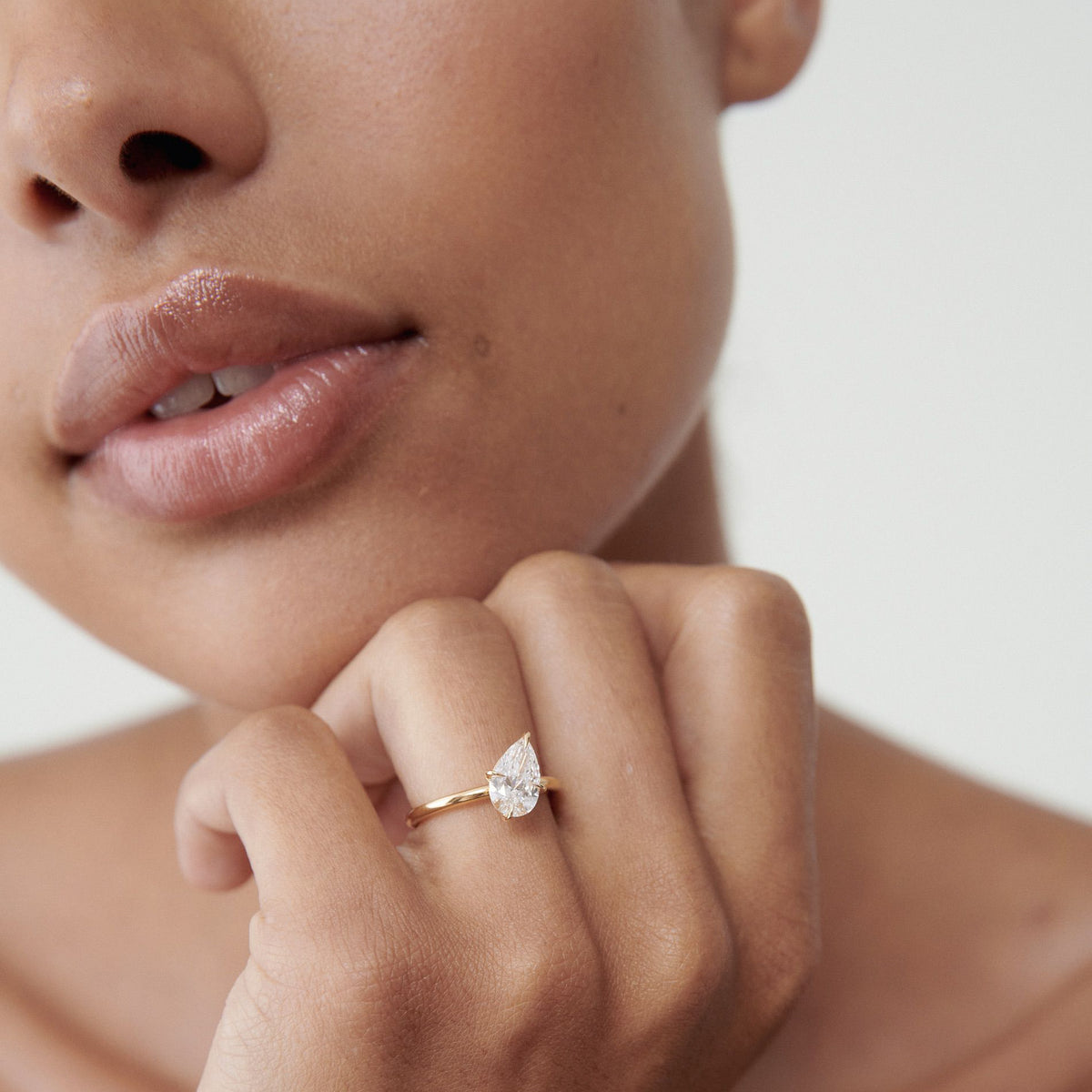 Close-up of a woman’s hand showcasing a gold ring set with a pear-shaped diamond, highlighting luxury jewellery against smooth skin.
