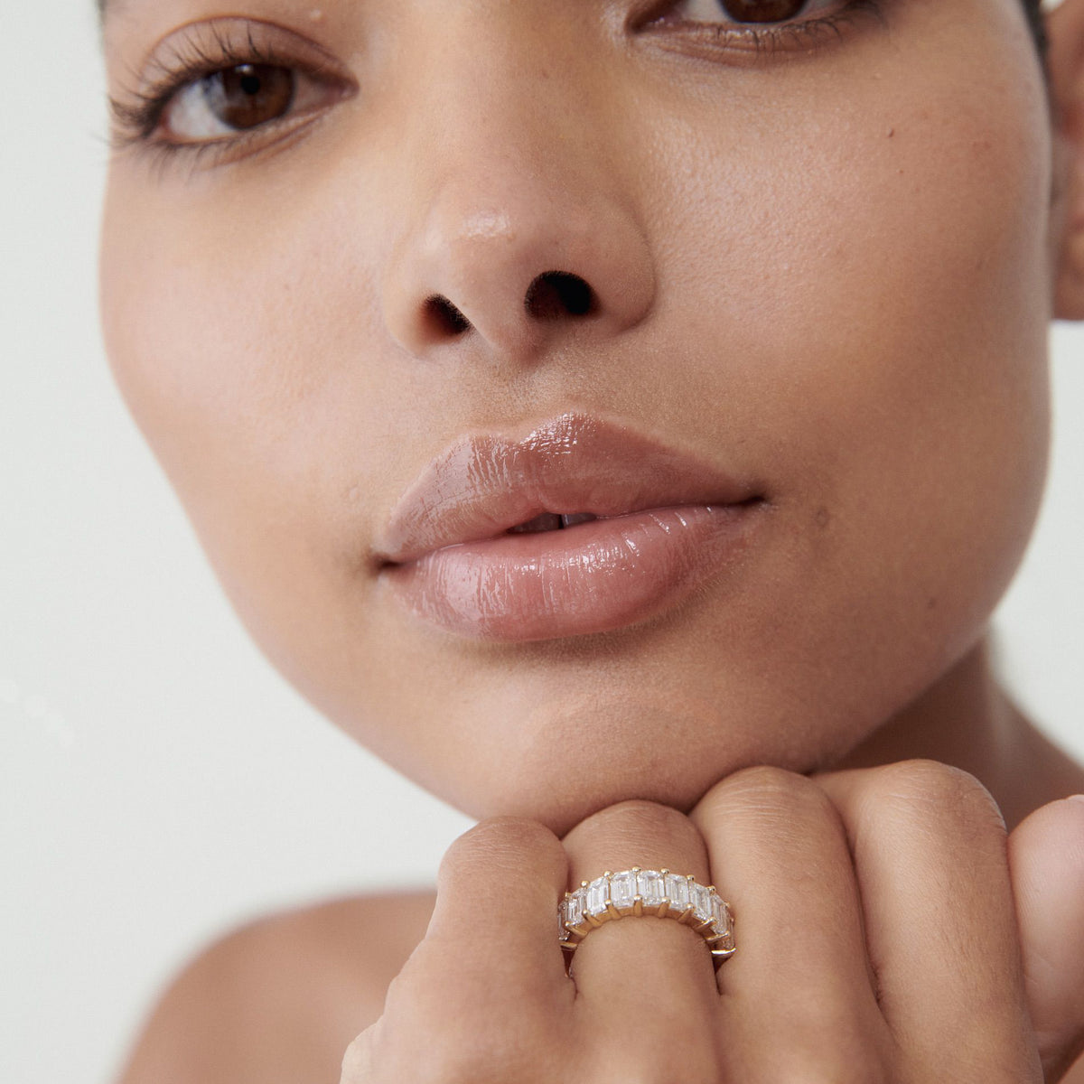 Close-up of a person wearing a luxurious diamond ring with baguette-cut stones, showcasing elegance and sophistication.[text overlay: Emerald] [text colour: #000000]

