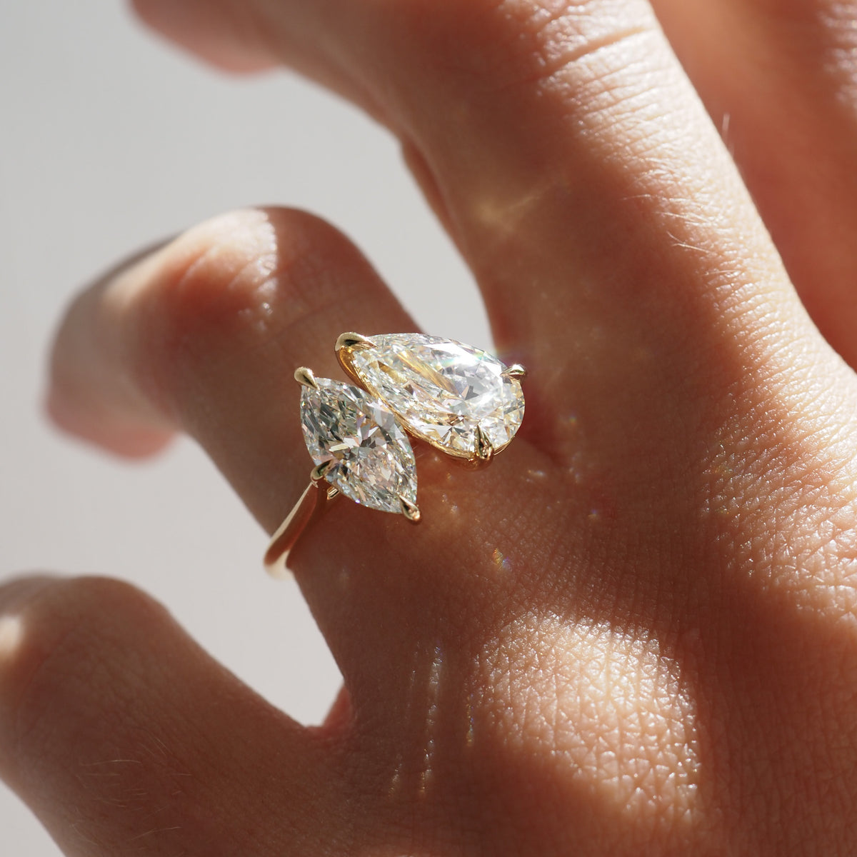 Gold-tone diamond ring worn on finger, pear and marquise stones with prongs