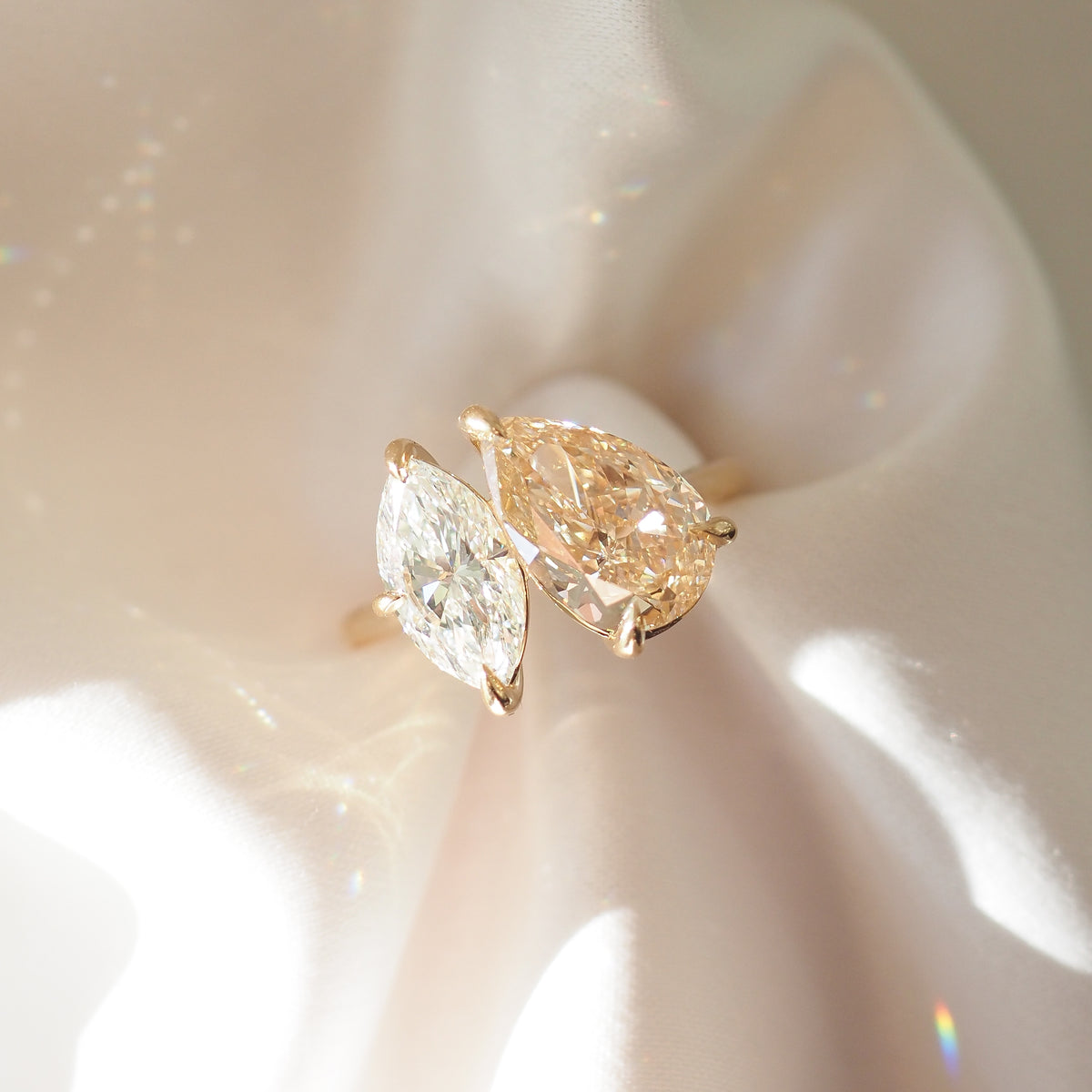 Close-up of champagne pear and marquise diamond toi et moi ring on gold-tone band