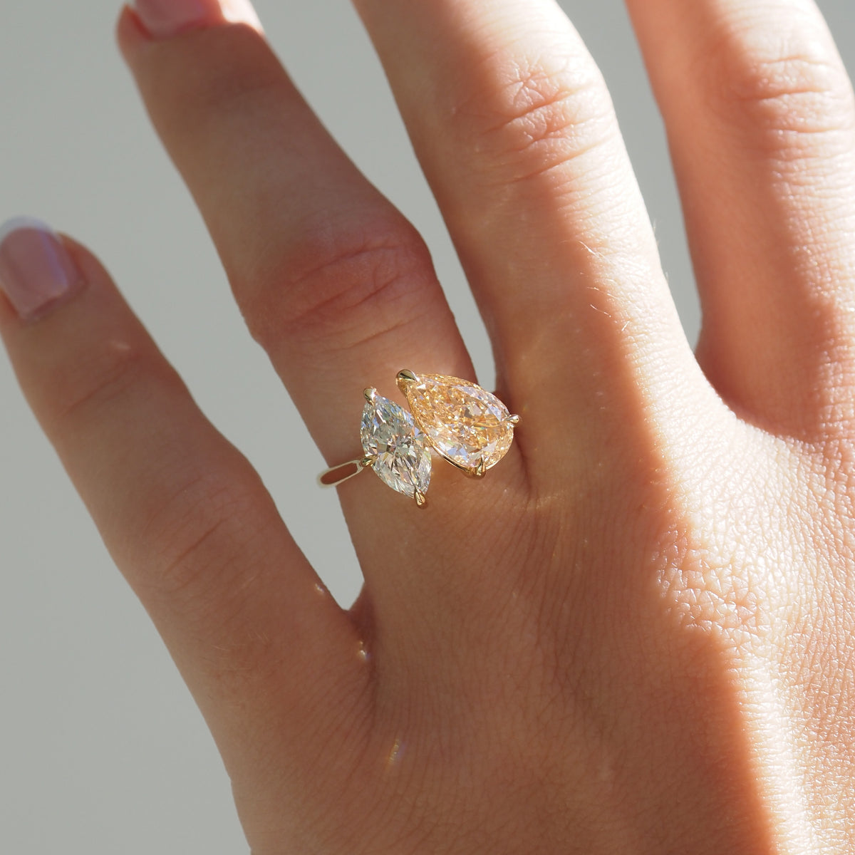 Champagne pear and marquise diamond toi et moi ring worn on hand, gold-tone band