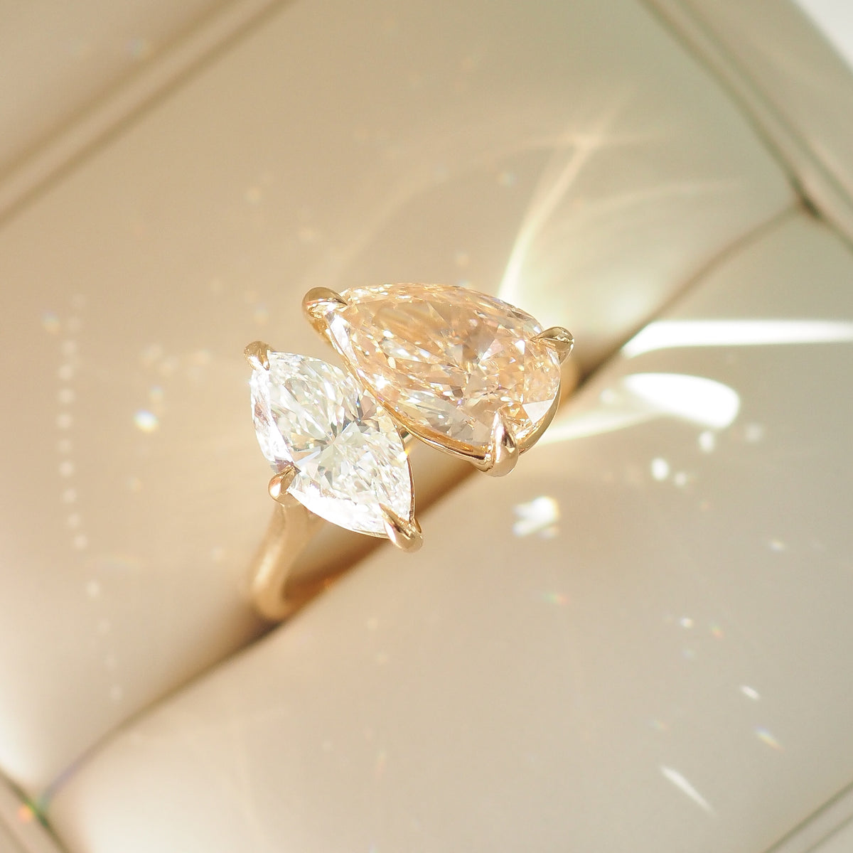 Side view of champagne pear and marquise diamond toi et moi ring on gold-tone band