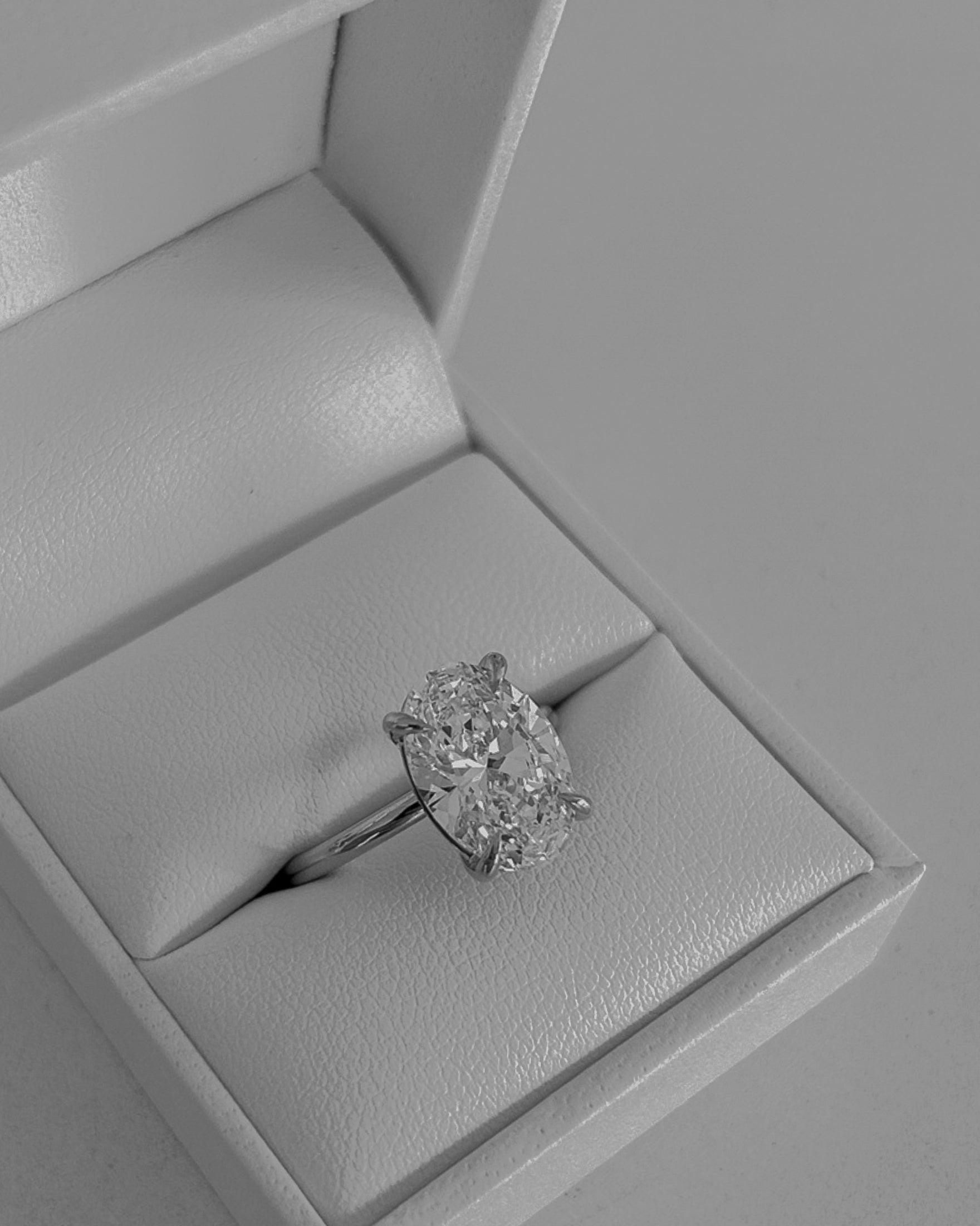 Oval diamond engagement ring in an open white jewellery box, showcasing luxury craftsmanship.