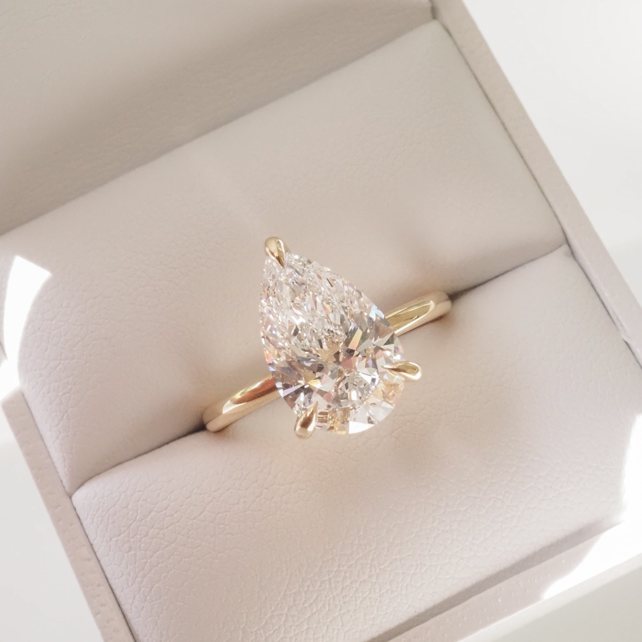 Gold ring featuring a pear-shaped diamond in an elegant jewellery box, capturing luxury and sophistication.
