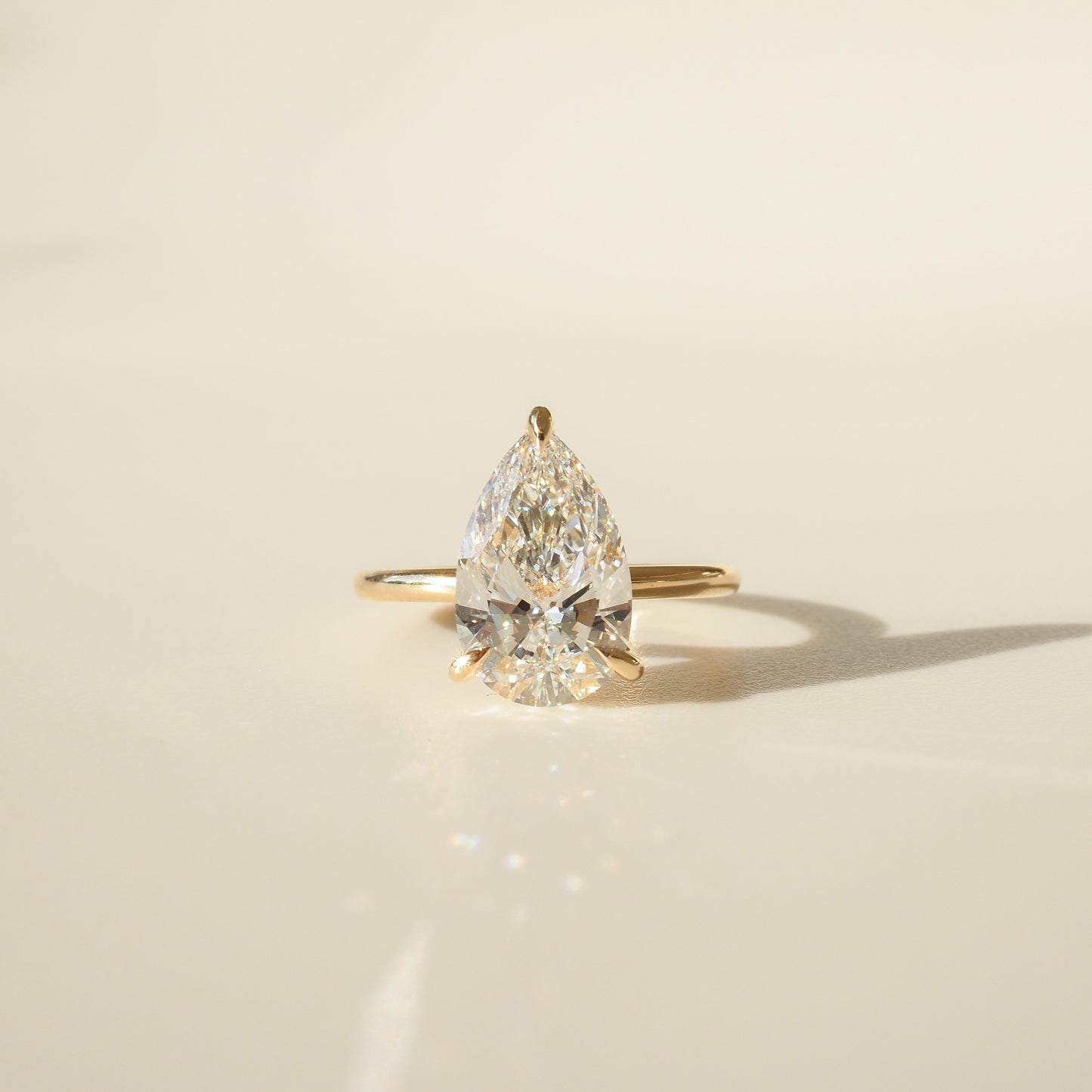Gold ring with a large pear-shaped diamond, elegantly displayed on a light background. Luxurious high-end jewellery.