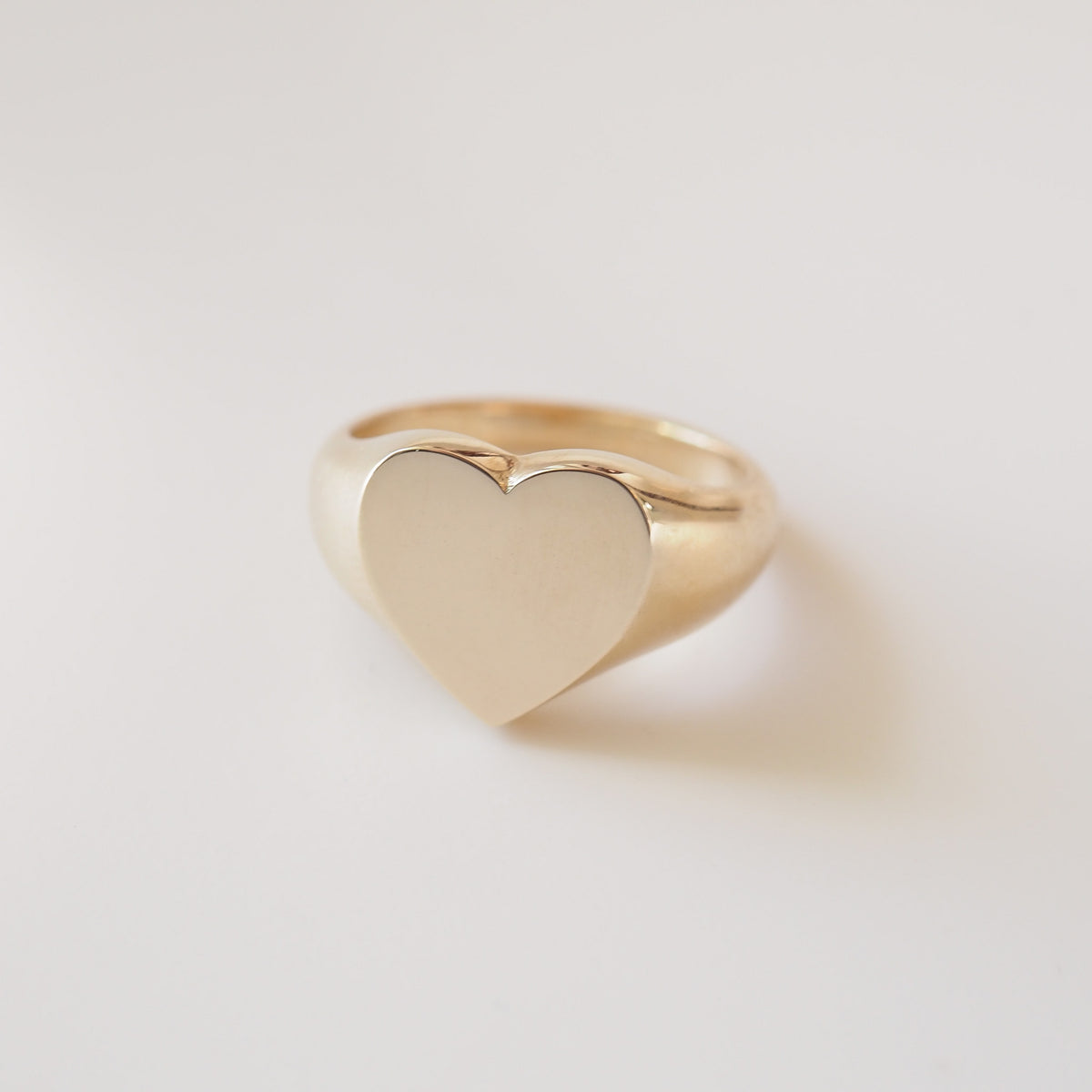 Gold heart-shaped ring on a light gray background