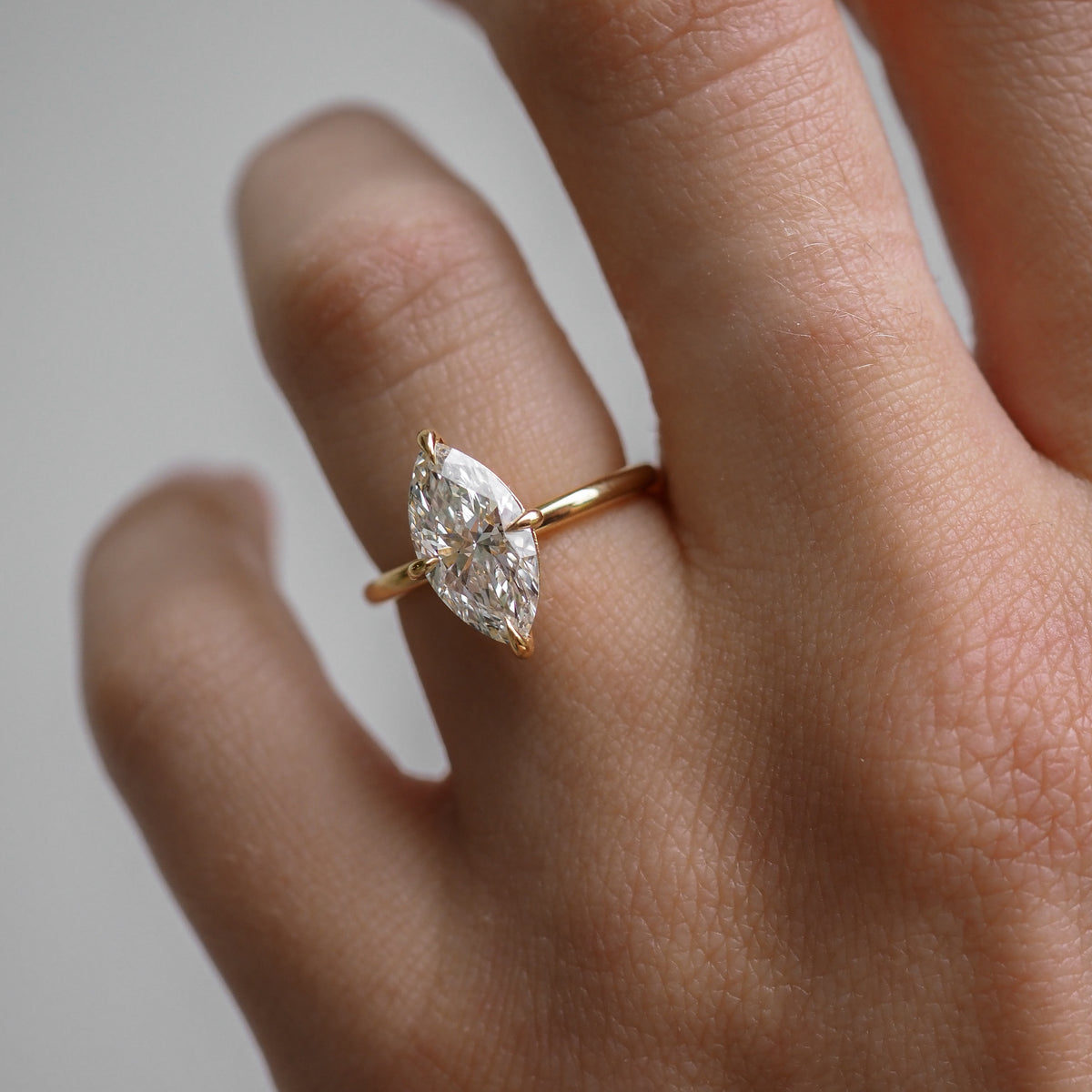 Close-up of a hand wearing a gold ring with a marquise-cut diamond, showcasing luxury jewellery craftsmanship and elegance.