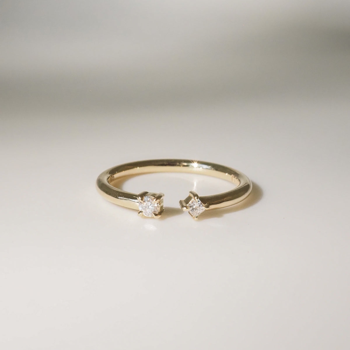 Elegant gold ring with two sparkling diamonds, set against a soft, light background. Perfect for luxury jewellery enthusiasts.