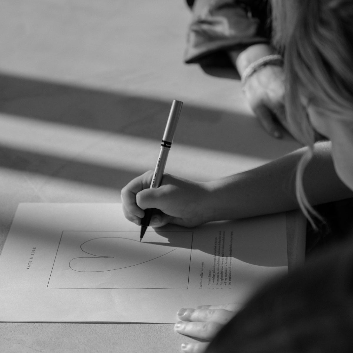 Hand sketching a heart design on paper, suggesting a creative process in luxury jewellery design.
