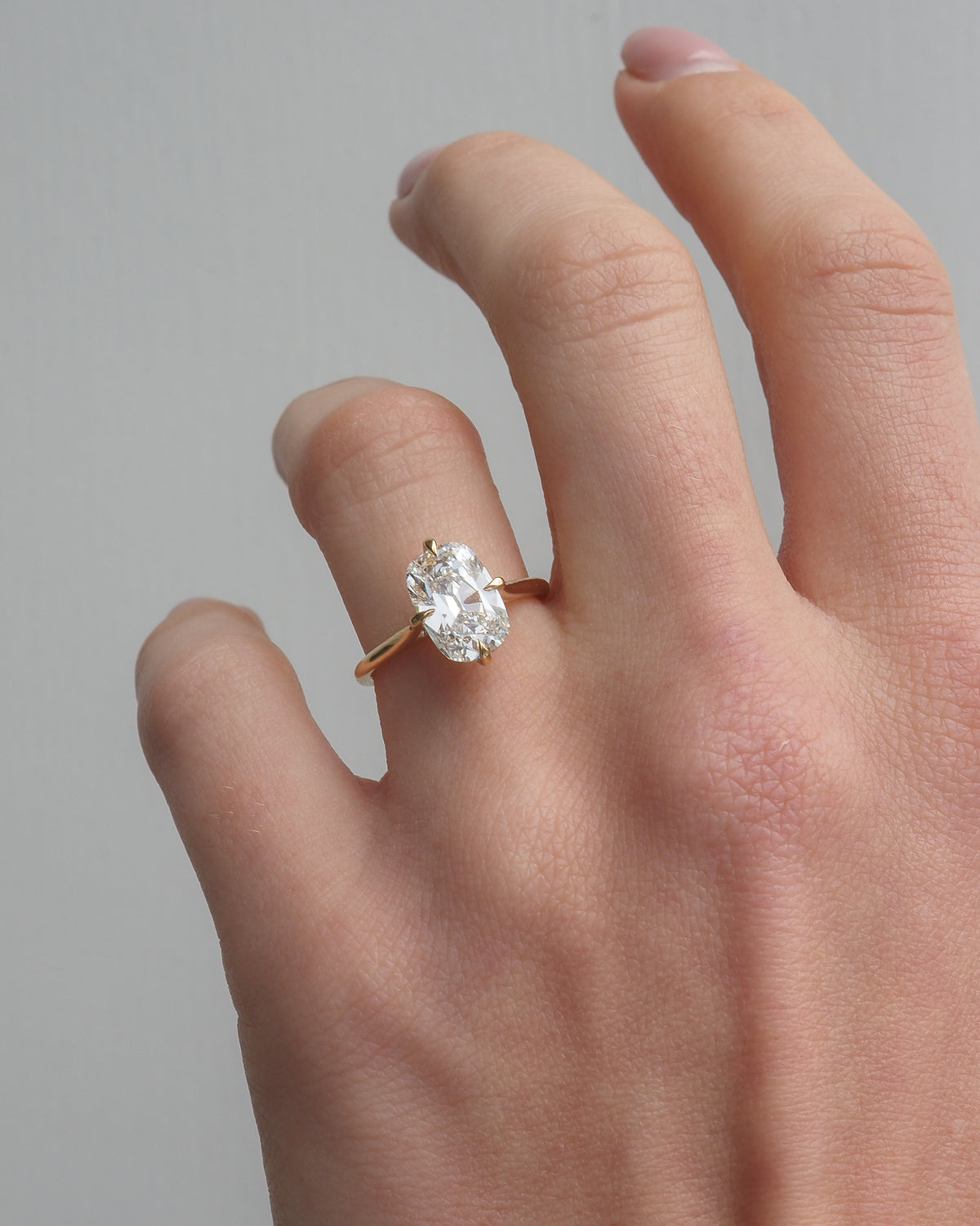Gold ring with cushion-cut lab-grown diamond, worn on finger