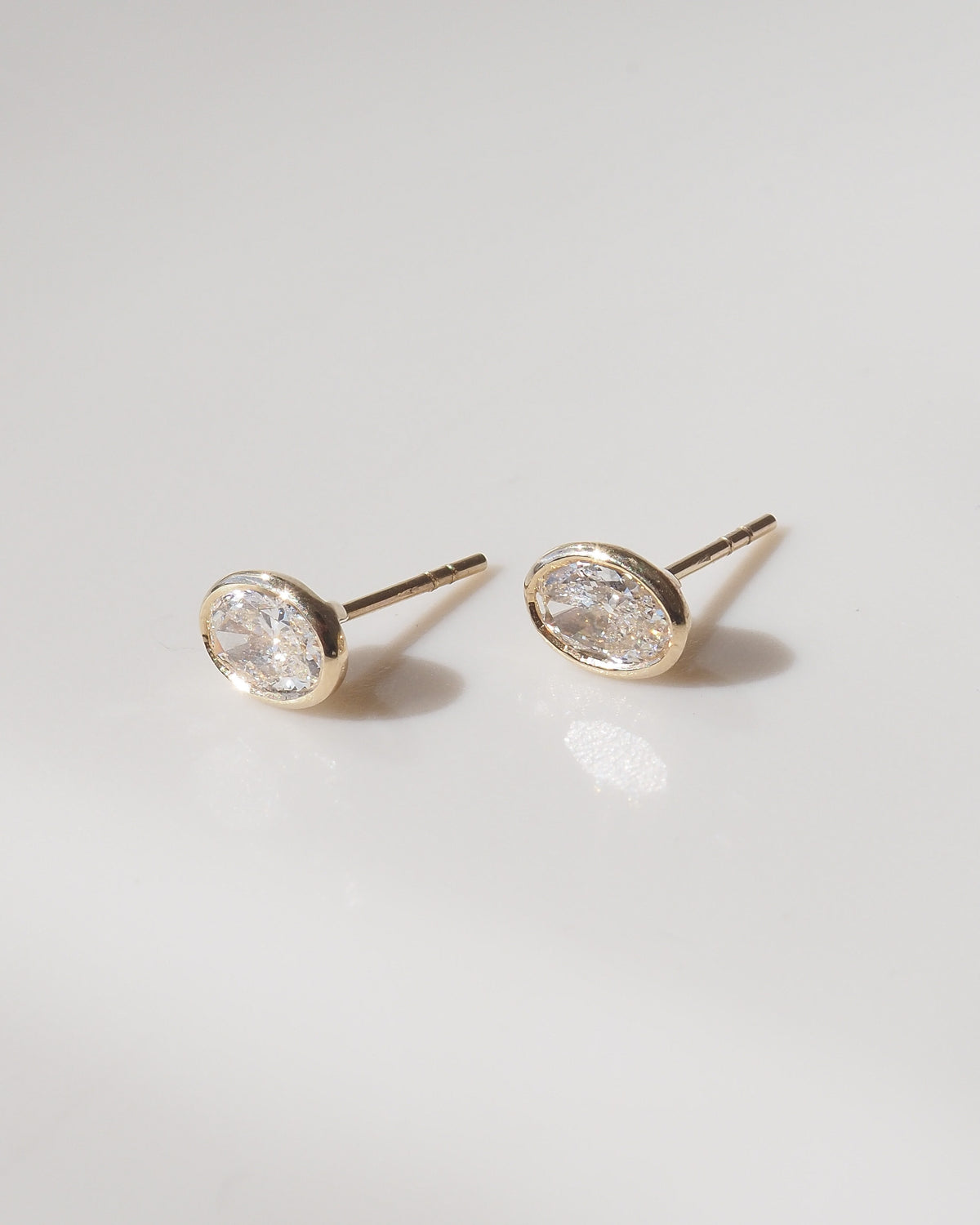 Oval bezel lab-grown diamond stud earrings with oval settings on gold posts