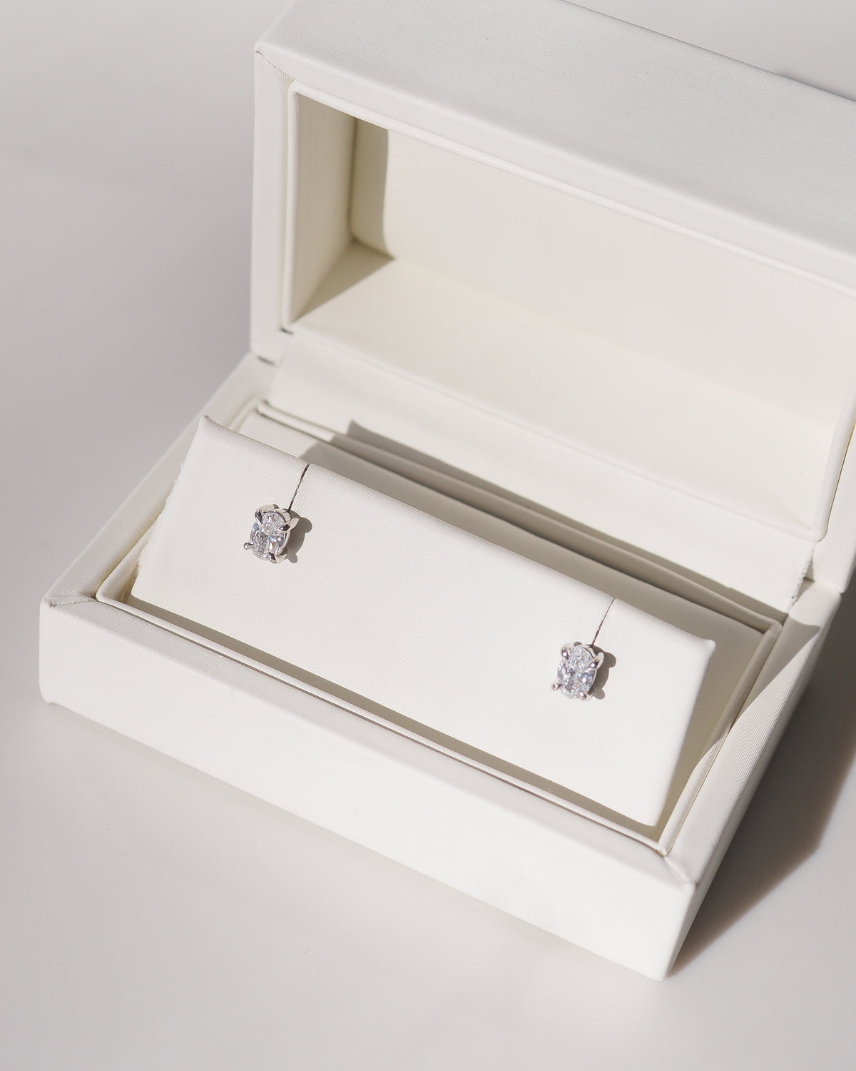 Oval 9ct white gold stud earrings with clear oval stones, four-prong settings