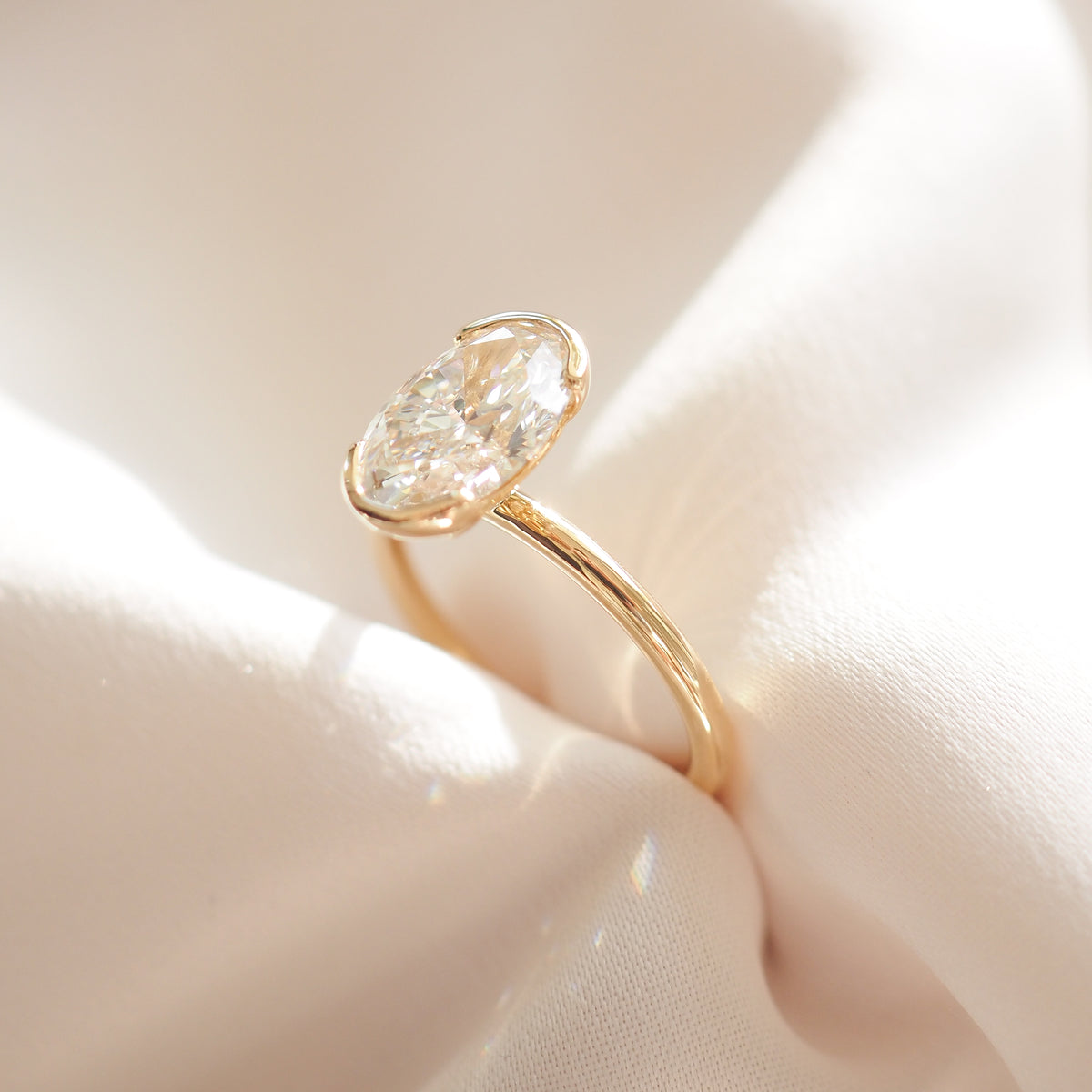 Gold oval lab-grown diamond solitaire ring, side view of half bezel setting