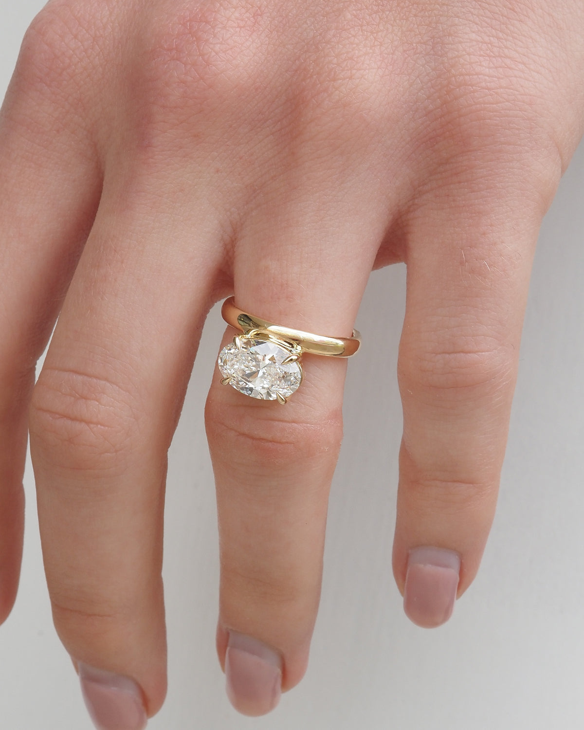 Gold band solitaire ring featuring an oval-cut diamond on top