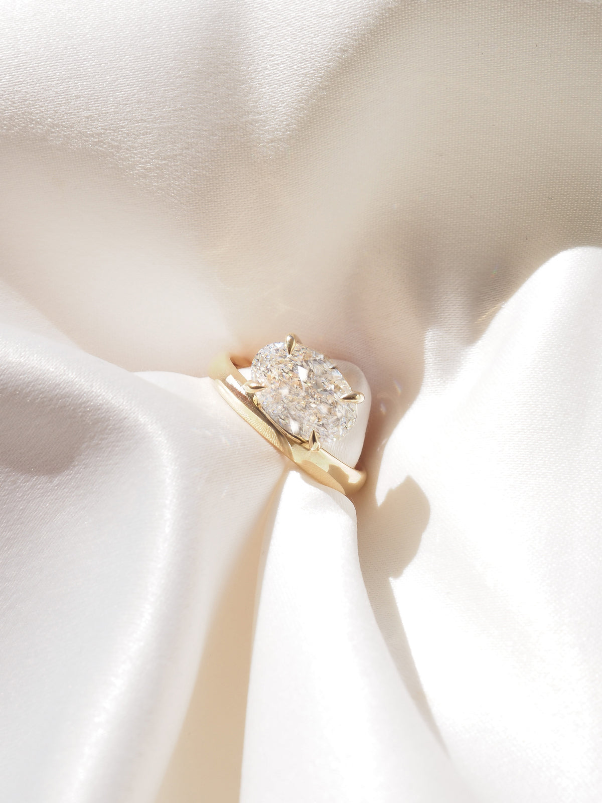 Gold solitaire ring with oval-cut diamond set in offset prongs