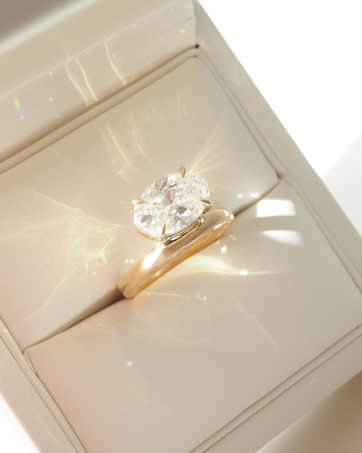 Gold solitaire ring with large oval-cut diamond, side halo detail