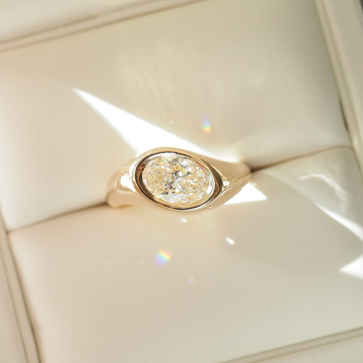 Gold ring with a diamond on a white cushion [text overlay: 1.5ct Riva Signet]