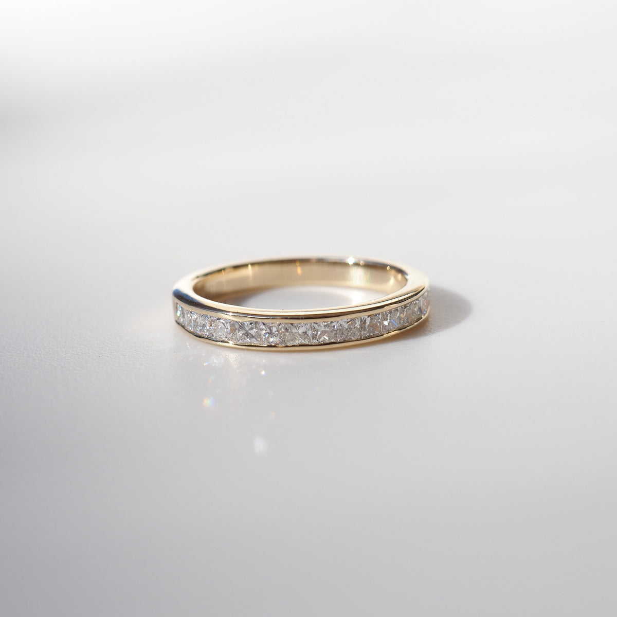 Gold band with embedded diamonds, elegantly displayed on a light background, showcasing luxury jewellery craftsmanship.