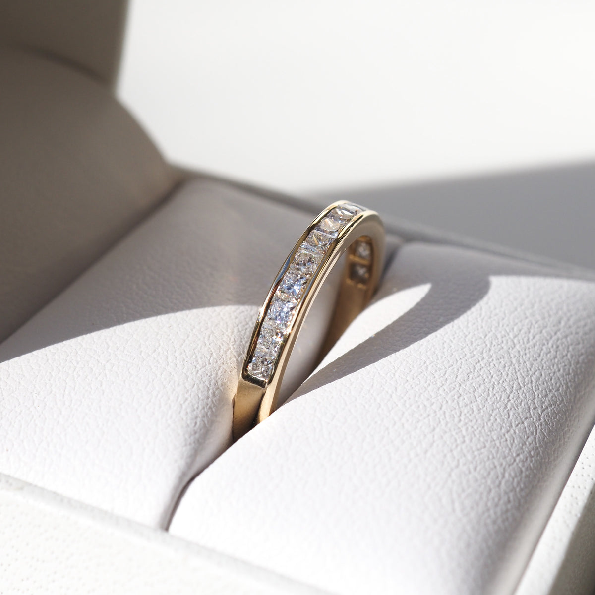 Gold diamond ring resting in a white jewellery box, showcasing an elegant and luxurious design. Ideal for special occasions or engagement.