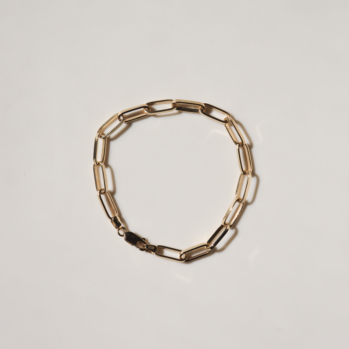 Gold link bracelet with elongated oval links and a lobster clasp on a white background. Luxurious and elegant jewellery piece.