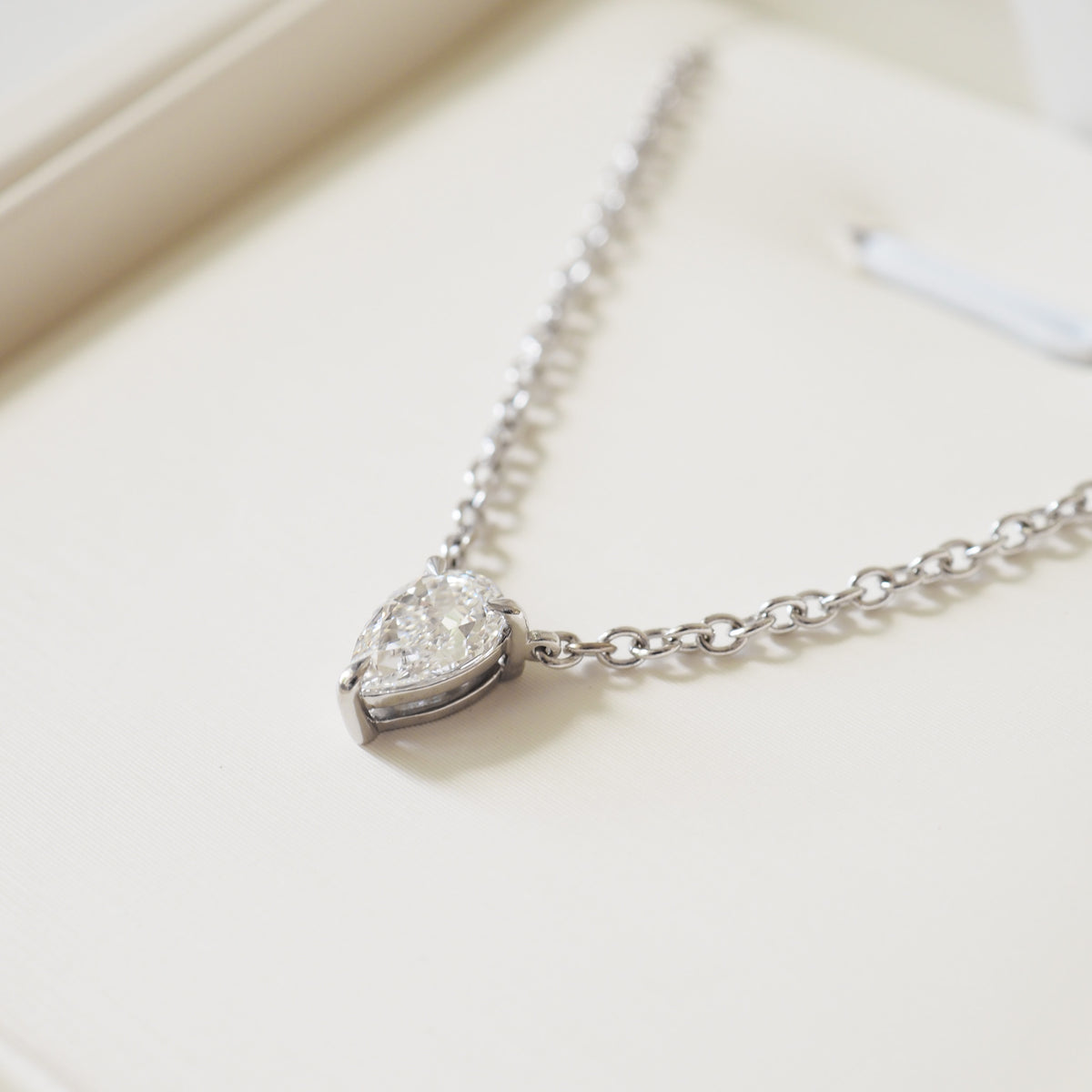 Close-up pear diamond pendant on silver link chain with secure setting