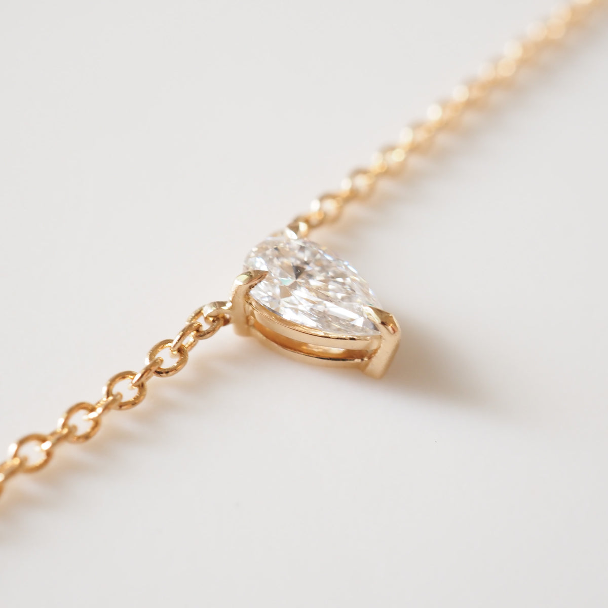 Gold chain pear-cut diamond necklace with bezel-set pendant, close-up