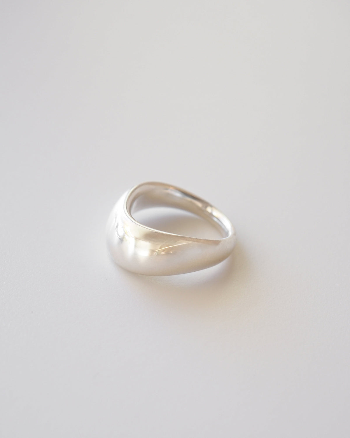A bold silver curved ring on a white background
