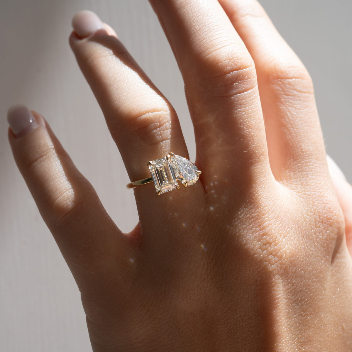 Yellow gold toi et moi ring on hand, emerald-cut and pear-shaped diamond stones