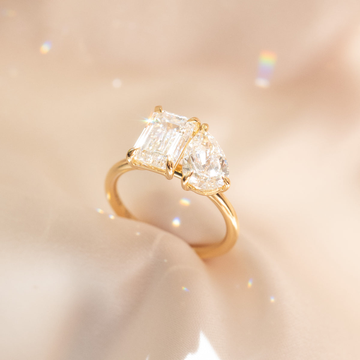 Close-up of yellow gold toi et moi ring with emerald-cut and pear-shaped diamonds