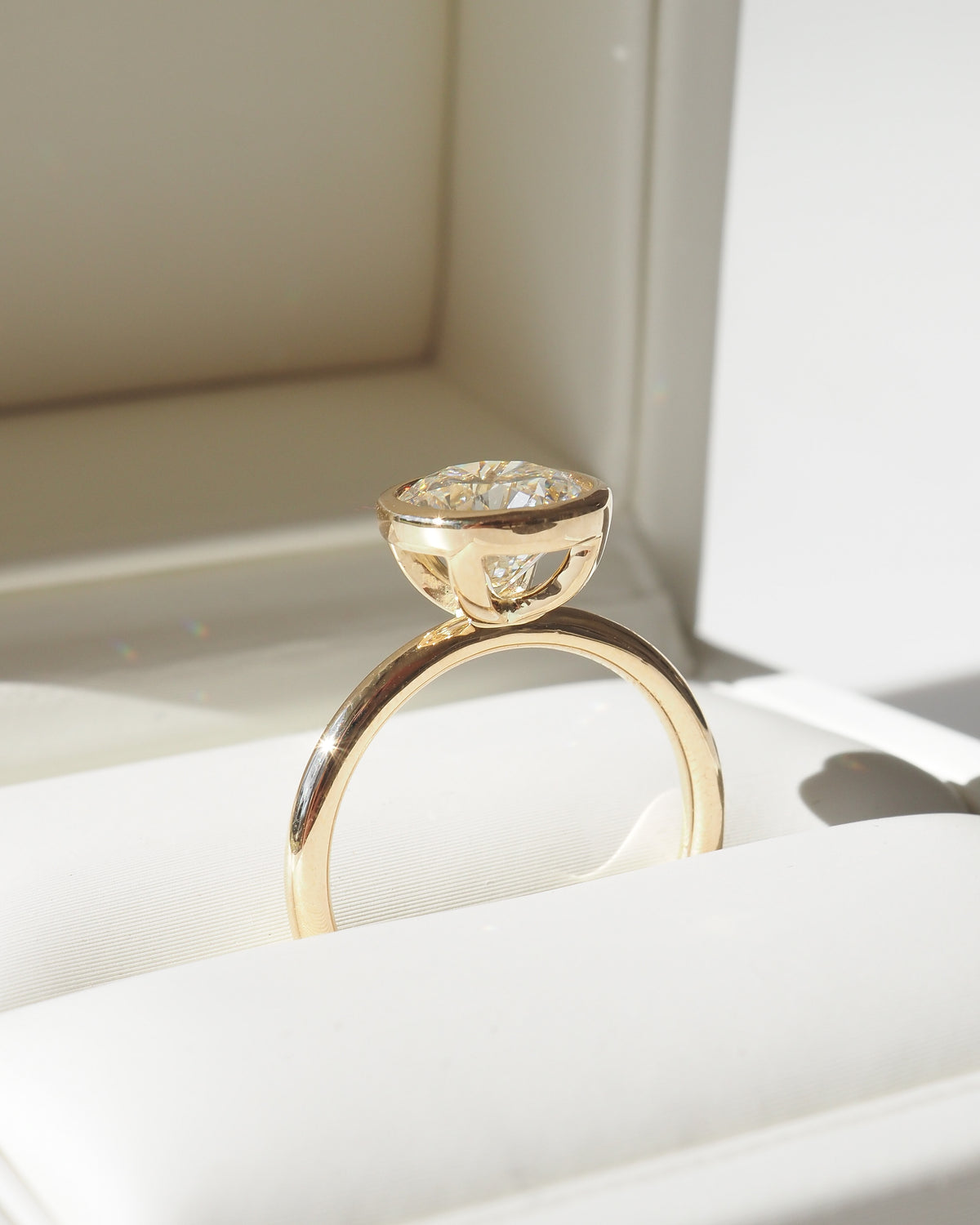 Gold solitaire engagement ring with round bezel-set diamond, side view