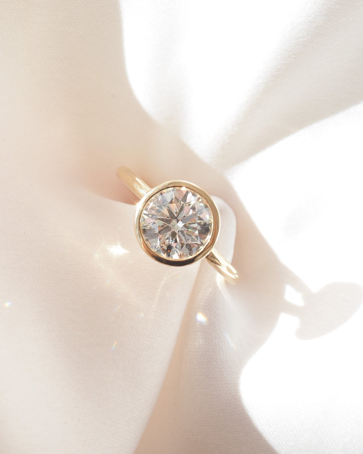 Gold bezel solitaire engagement ring with bright round center stone