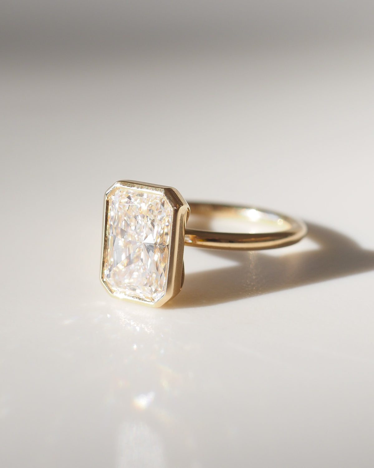 Gold band ring with square bezel-set radiant-cut diamond, side view