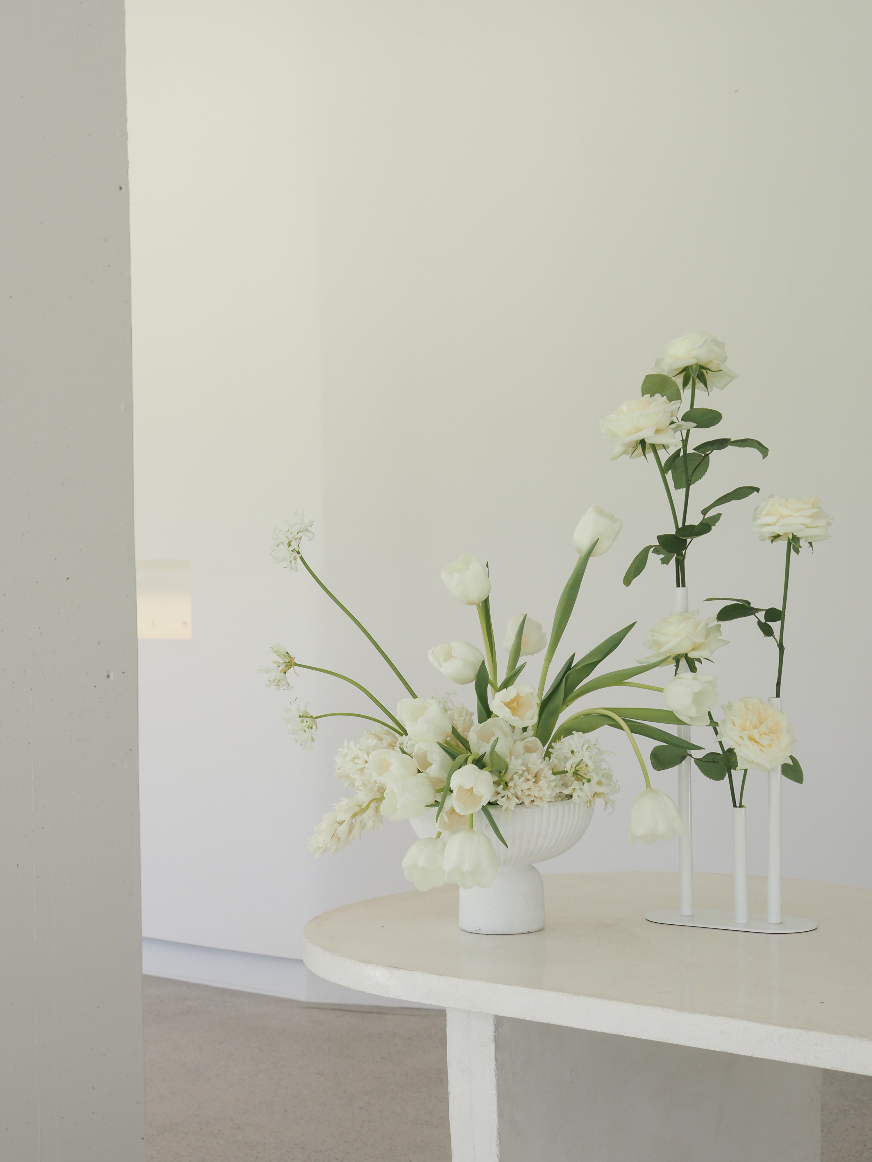 Elegant white flowers in ceramic vases on a minimalist white table, creating a sophisticated and luxurious aesthetic.