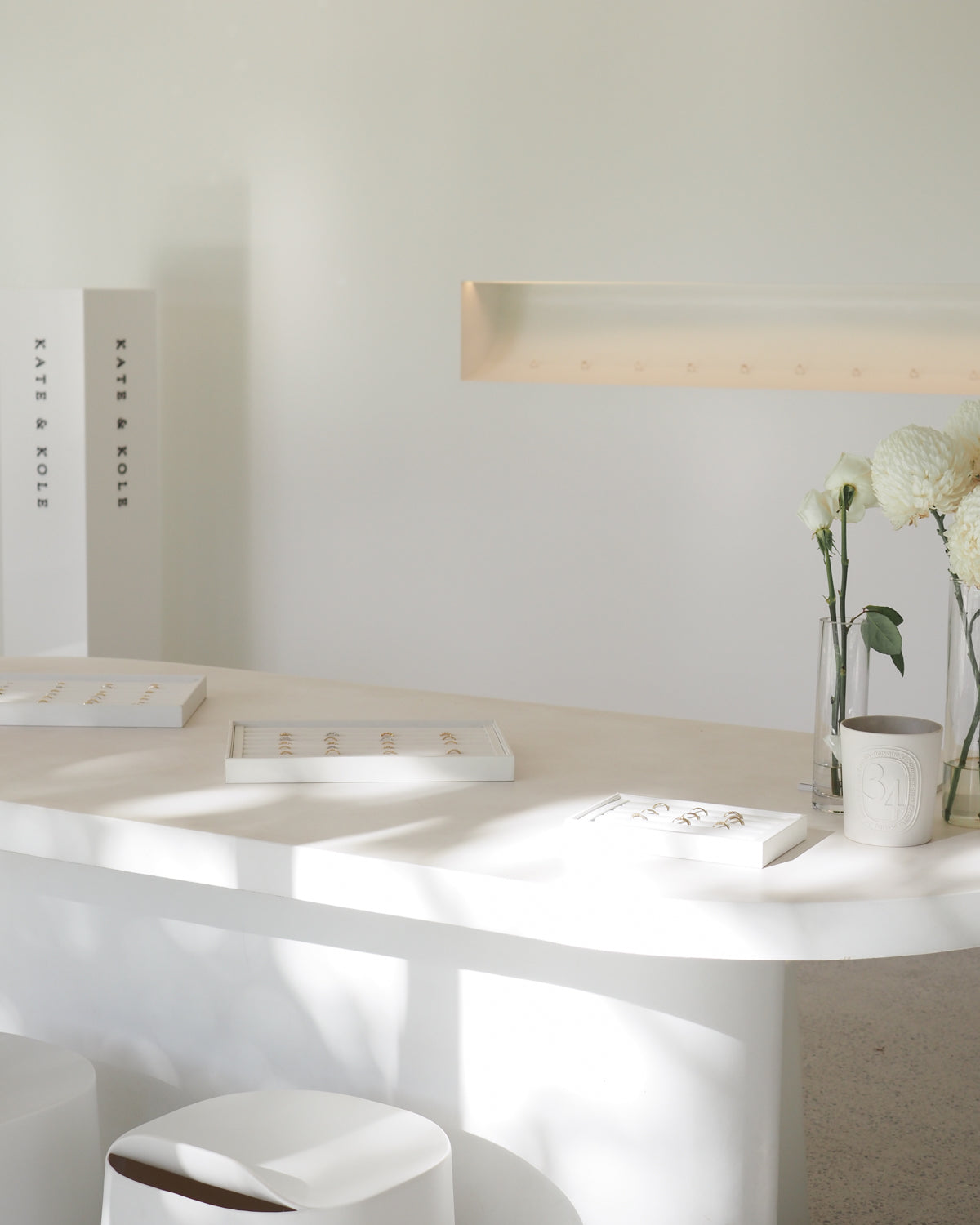 Minimalist jewellery display with white boxes, floral decor, and gold accents. Bright, airy ambience in a luxury Australian boutique setting.