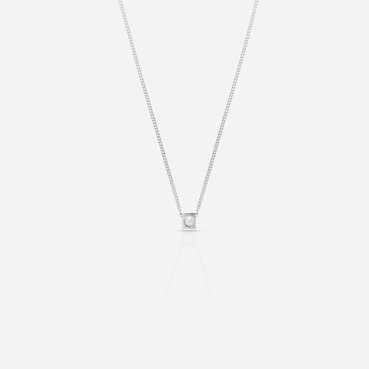 Elegant solitaire diamond pendant on a delicate silver chain, set against a light background, showcasing luxury and sophistication.
