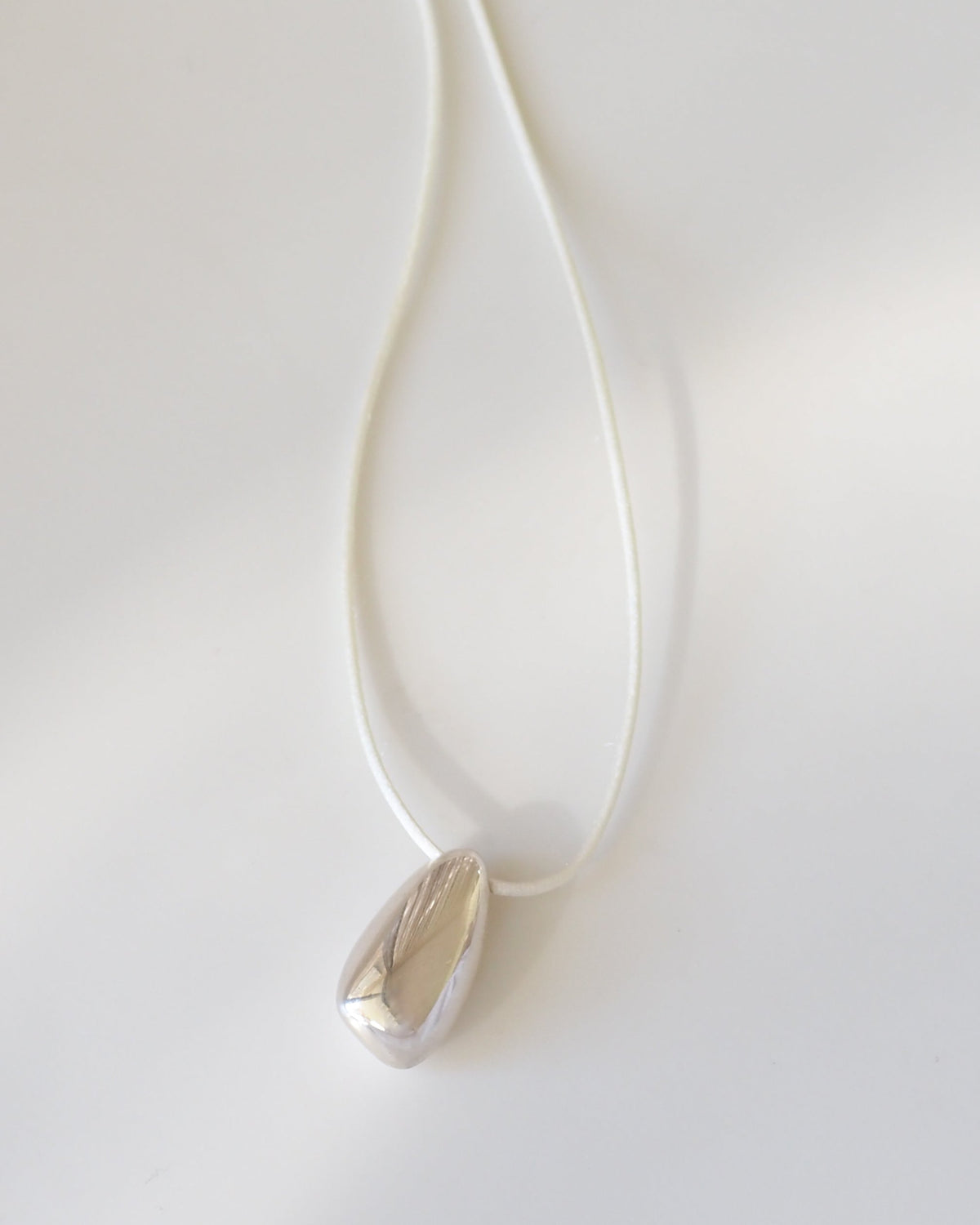 Silver necklace with a teardrop pendant on a white background