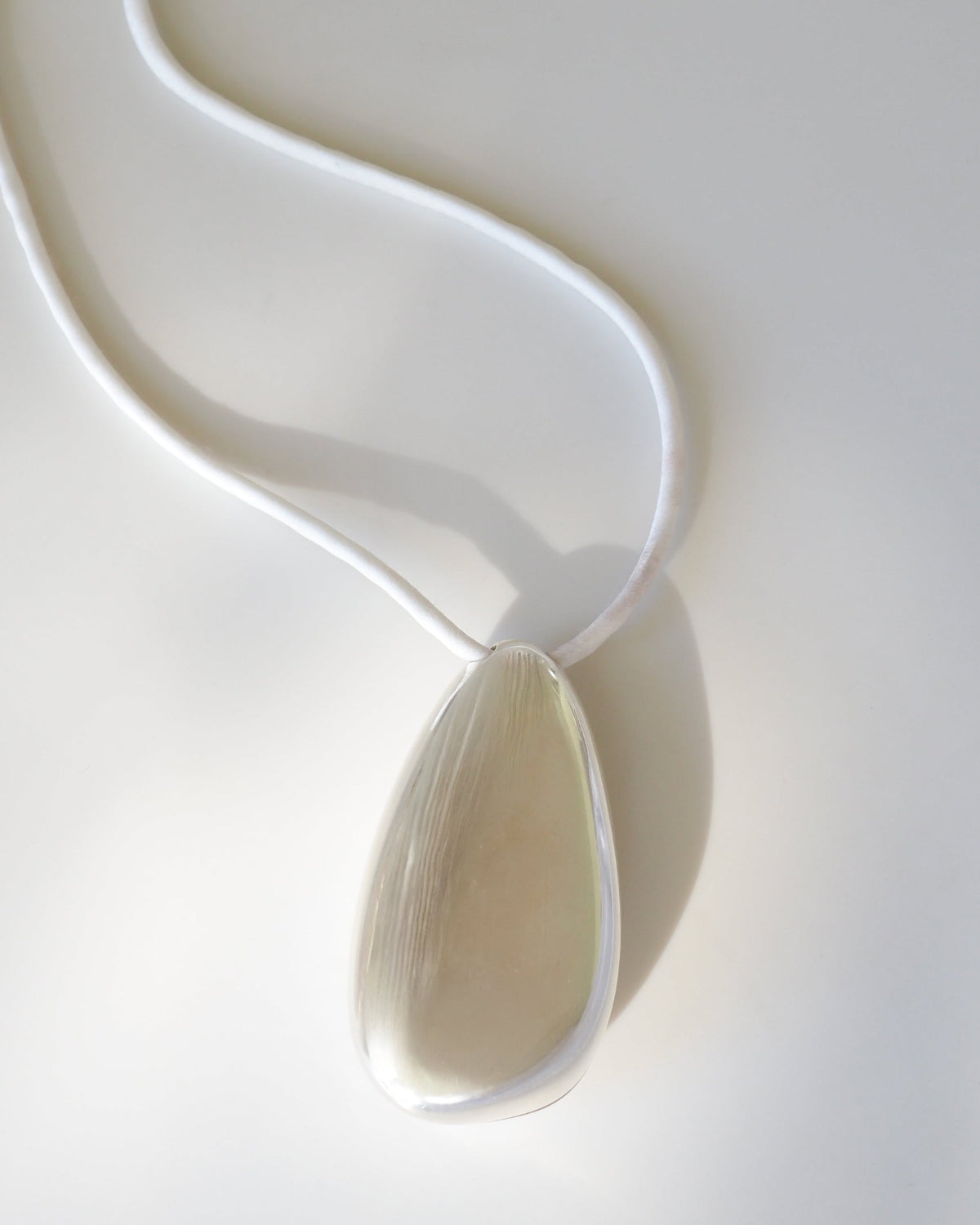Silver pebble shaped pendant white background