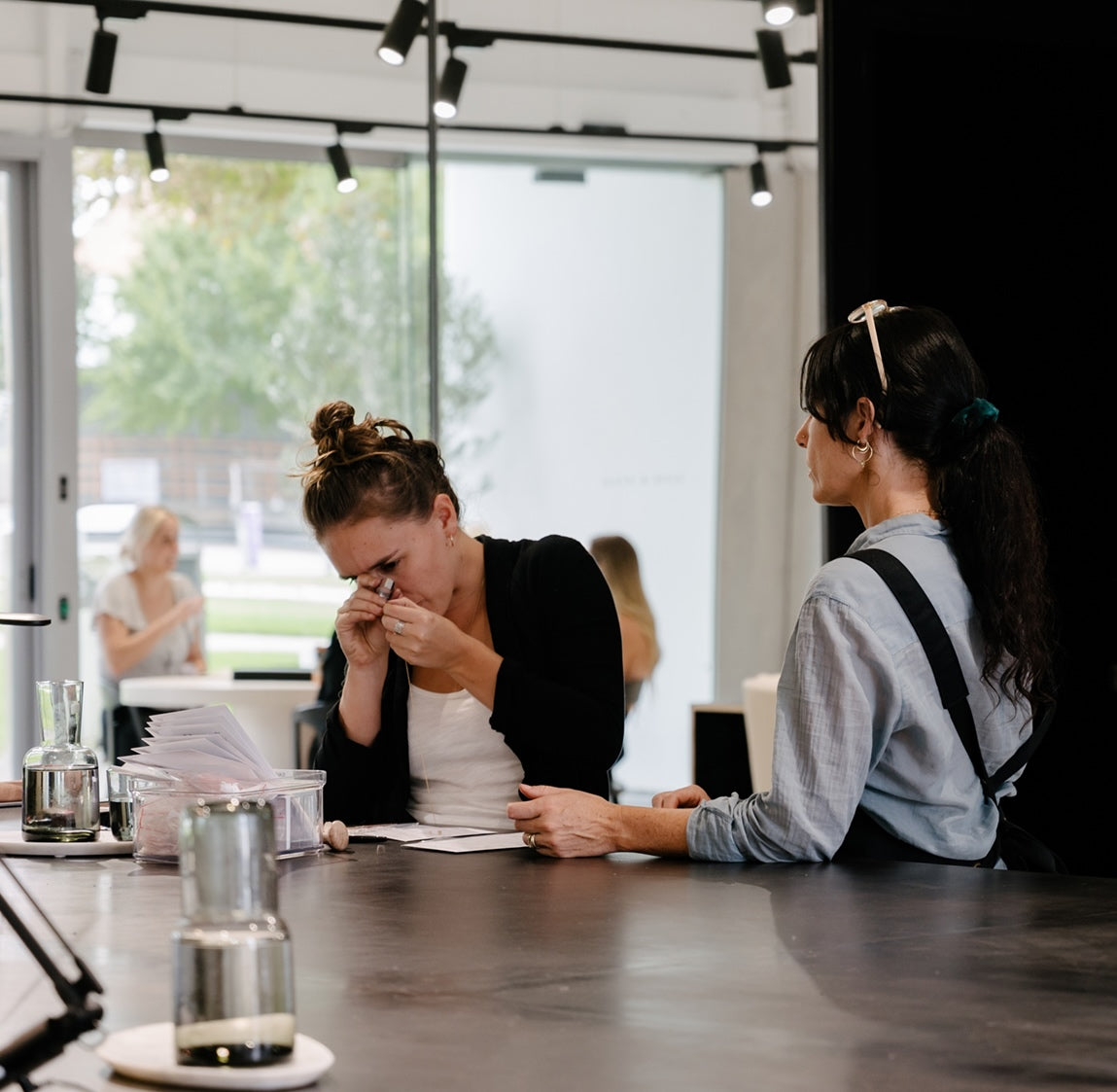 Two women evaluating jewellery at a luxury store counter, with one examining a piece using a loupe, highlighting attention to detail.